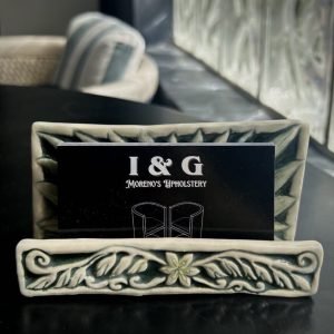 New business cards for Moreno's Upholstering placed in a business card holder made out of ceramics with floral etchings.